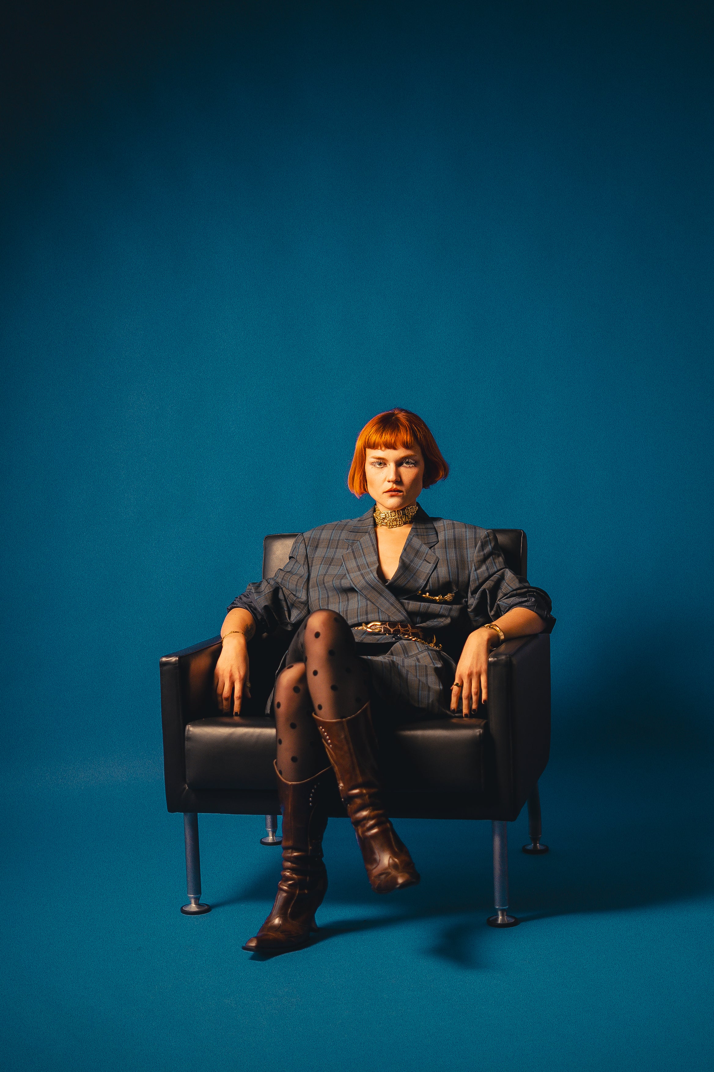 Femme rousse assise sur un fauteuil en cuir noir